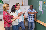 Creative business people clapping hands by blackboard