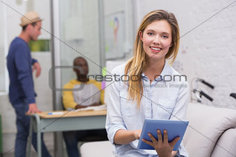 Casual woman using digital tablet with colleagues behind in office