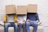Casual people sitting on couch with boxes over heads