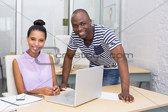 Casual colleagues using laptop in office