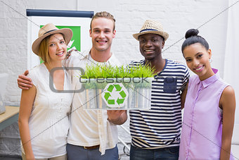 Creative business team holding plant with recycling symbol