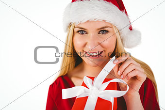 Festive blonde in red dress opening a gift
