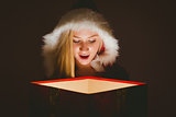 Festive blonde looking into glowing gift