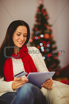 Pretty brunette shopping online with tablet at christmas