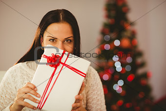 Pretty brunette holding christmas present on couch