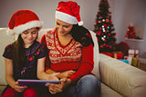 Festive mother and daughter using tablet