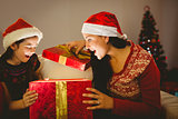 Festive mother and daughter opening a glowing christmas gift