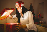 Festive brunette opening a glowing christmas gift