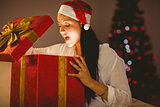 Festive brunette opening a glowing christmas gift