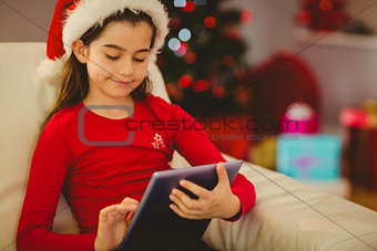 Festive little girl using tablet pc on couch
