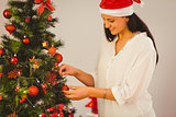 Woman hanging christmas decorations on tree
