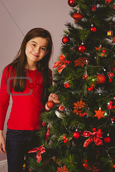 Little girl smiling at camera beside christmas tree