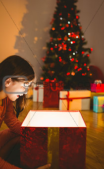 Little girl opening a glowing christmas gift