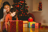 Festive mother and daughter opening a glowing christmas gift