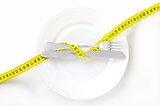Measuring tape on a fork and knife - dieting concept image