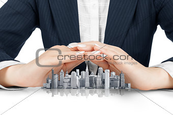 Female hands saving small city with a roof