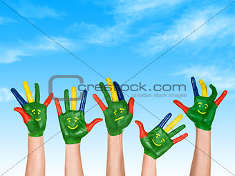 Image of human hands in colorful paint with smiles on the backgr