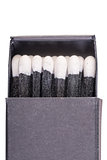 Black matches in a box on a white background macro