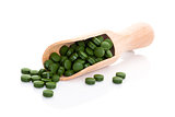 Green pills on wooden scoop.