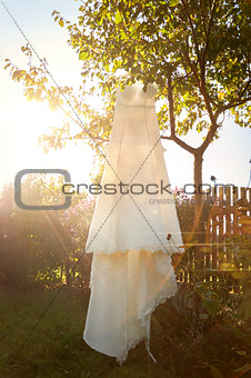 romantic wedding dress hanging from a tree