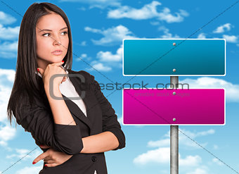 Thoughtful businesswoman and road sign