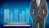 Businessman and wire-frame buildings on screen tablet pc