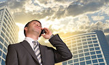 Businessman talking on the phone. Skyscrapers and clouds