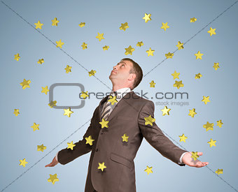 Businessman spread his arms. Gold stars fall from above