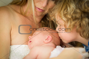 Young Mother Holds Newborn Baby Girl as Brother Kisses Her