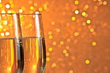 pair of a champagne flutes on orange and yellow light bokeh background