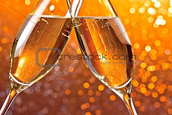 detail of champagne flutes on orange light bokeh background