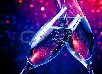 champagne flutes with gold bubbles on blue tint light bokeh background