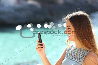 Woman using a smart phone in a tropical beach in vacations