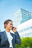 Smiling business woman talking mobile phone in office district