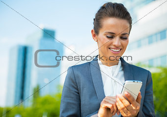 Happy business woman writing sms in office district