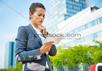 Thoughtful business woman with tablet pc in office district