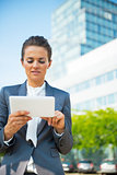 Business woman using tablet pc in front of office building