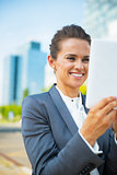 Happy business woman using tablet pc in office district
