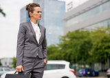 Business woman with briefcase standing in office district and lo