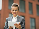 Business woman using tablet pc in front of office building