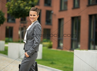 Portrait of business woman with briefcase in front of office bui