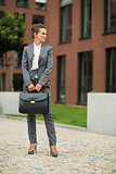 Full length portrait of business woman with briefcase in front o
