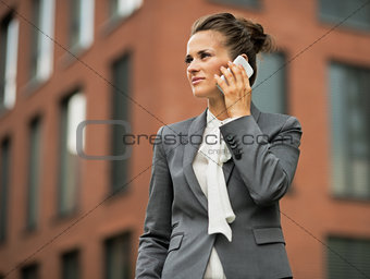 Business woman talking mobile phone in front of office building