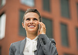 Happy business woman talking cell phone in front of office build