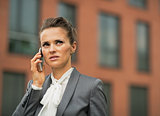 Serious business woman talking cell phone in front of office bui