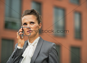 Serious business woman talking cell phone in front of office bui