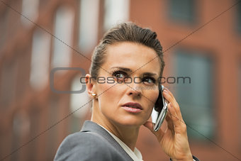 Portrait of serious business woman talking cell phone in front o