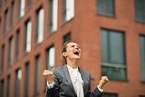 Happy business woman rejoicing in front of office building
