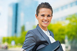 Portrait of smiling business woman with briefcase in office dist