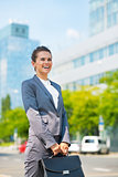 Happy business woman with briefcase in office district